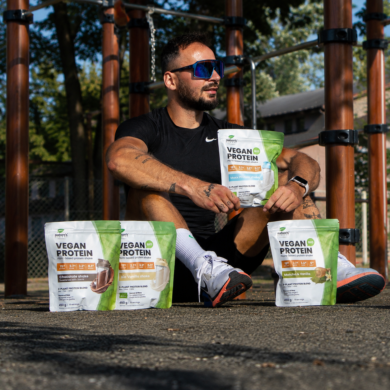 Man outdoors holding Nature’s Finest Vegan Protein pouches (Chocolate, Bio Vanilla, Bio Matcha Vanilla)