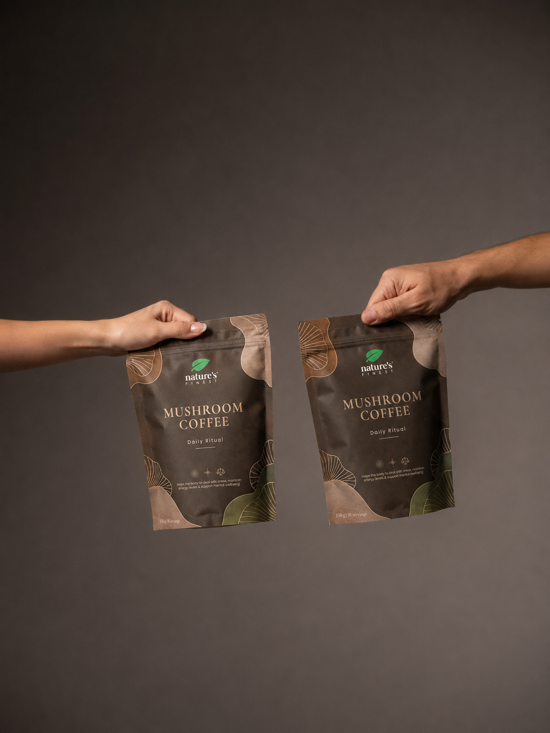 Two hands exchanging Nature’s Finest Mushroom Coffee pouches on a studio background